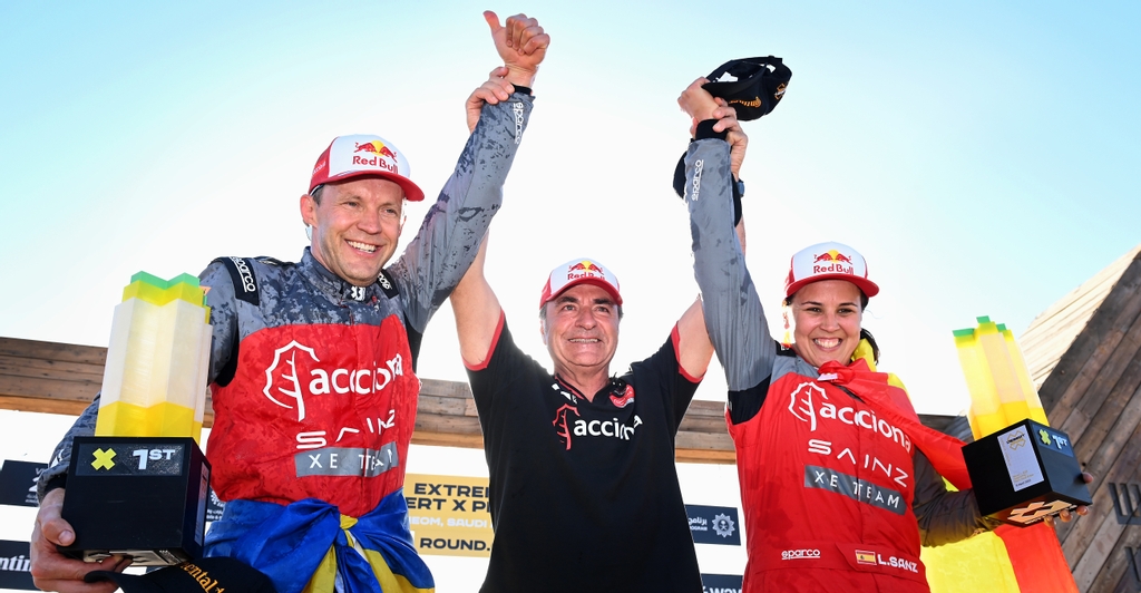 MARCH 12: Mattias Ekstrom (SWE), Acciona | Sainz XE Team, and Laia Sanz (ESP), Acciona | Sainz XE Team, 1st position, celebrate with Carlos Sainz (ESP), Acciona | Sainz XE Team, on the podium during the Desert X-Prix on March 12, 2023. (Photo by Sam Bagnall / LAT Images)