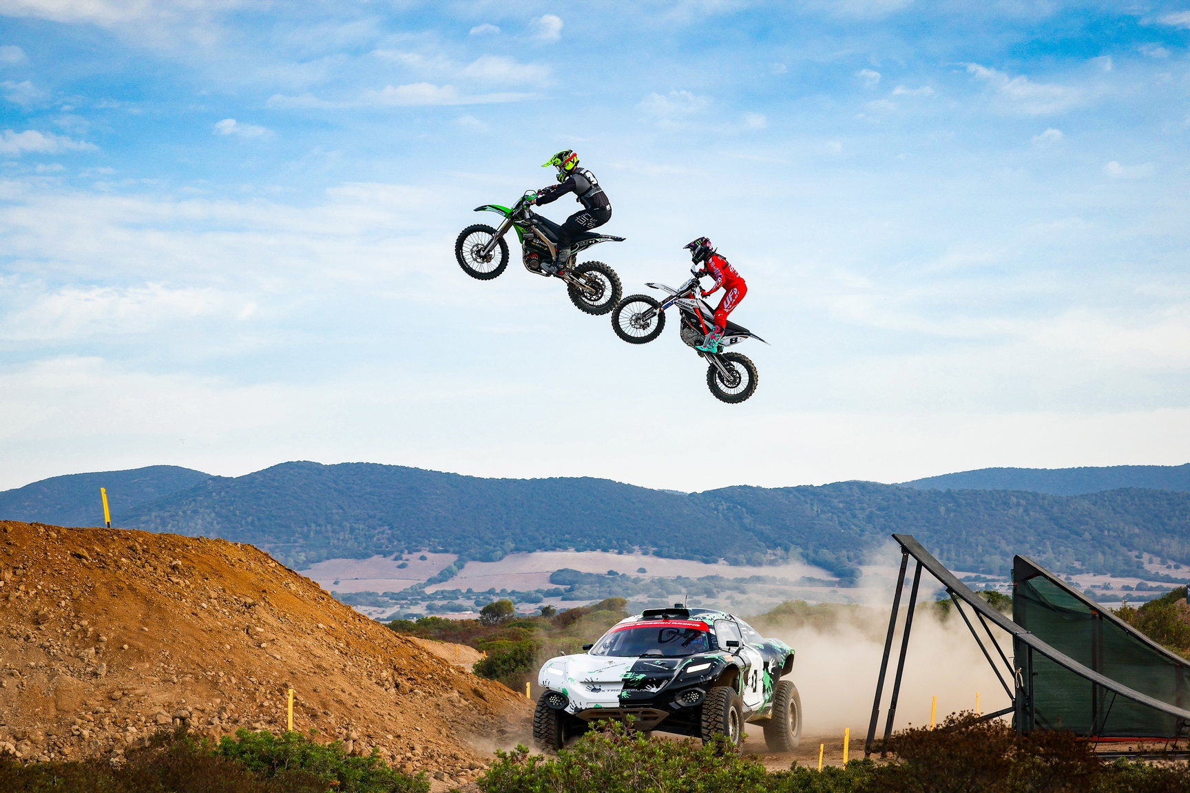 CAPO TEULADA, SARDINIA, ITALY - SEPTEMBER 14: E-Explorer bikes jump over the Championship Car during the Island X-Prix II on September 14, 2023 in Capo Teulada, Sardinia, Italy. (Photo by Colin McMaster / LAT Images)