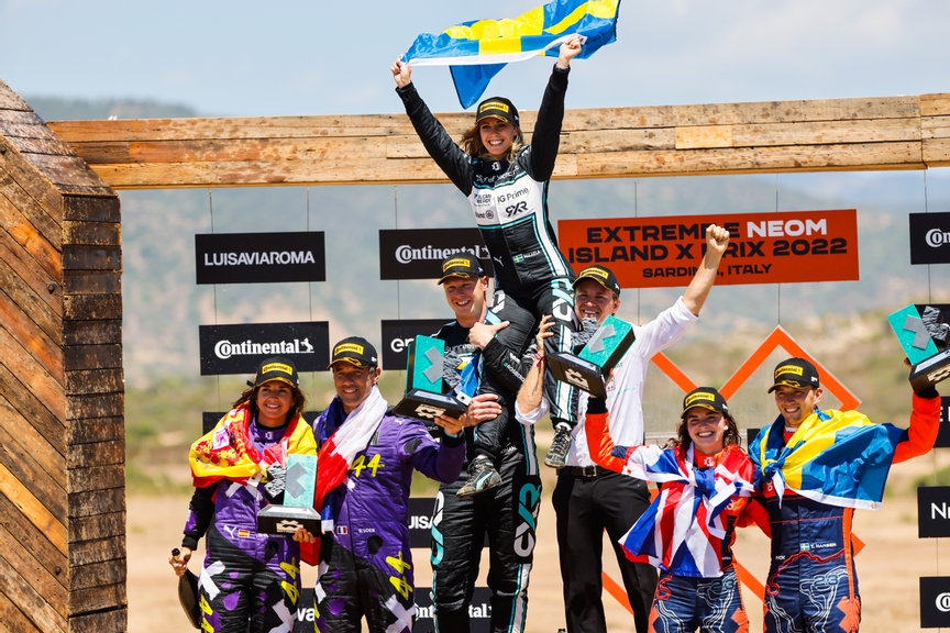 CAPO TEULADA, SARDINIA, ITALY - JULY 10: Winners Mikaela Ahlin-Kottulinsky (SWE), Rosberg X Racing, and Johan Kristoffersson (SWE), Rosberg X Racing, celebrate on the podium with Nico Rosberg, Sebastien Loeb (FRA), Team X44, Cristina Gutierrez (ESP), Team X44, Catie Munnings (GBR), Genesys Andretti United Extreme E and Timmy Hansen (SWE), Genesys Andretti United Extreme E during the Sardinia II on July 10, 2022 in Capo Teulada, Sardinia, Italy. (Photo by Andrew Ferraro / LAT Images)